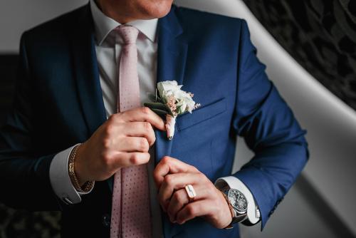 wedding details - elegant groom dressed in fashion costume with luxury boutonniere is waiting for the bride